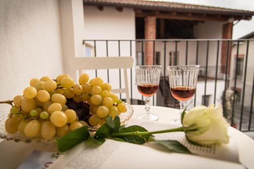 a table with two glasses of wine and a bowl of grapes at Acini e Rose in Montalenghe