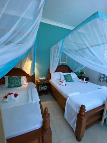 two beds in a room with blue walls at Pumzika Kendwa Villa in Kendwa