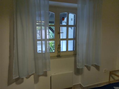 una ventana con cortinas blancas en una habitación en Sirály Apartman, en Révfülöp