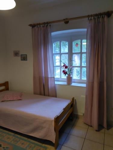 レーヴフュロップにあるSirály Apartmanのベッドルーム1室(ベッド1台付)、花の咲く窓が備わります。