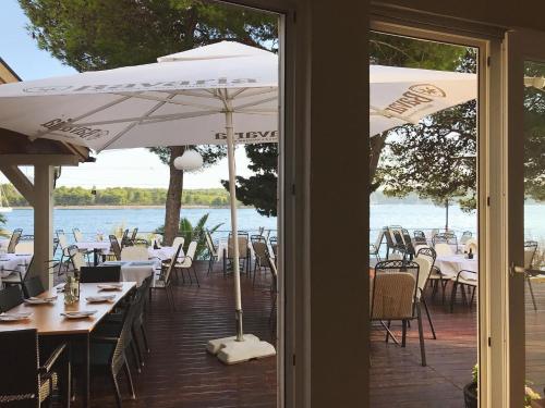 a patio with tables and chairs and an umbrella at Illyrian Resort in Milna