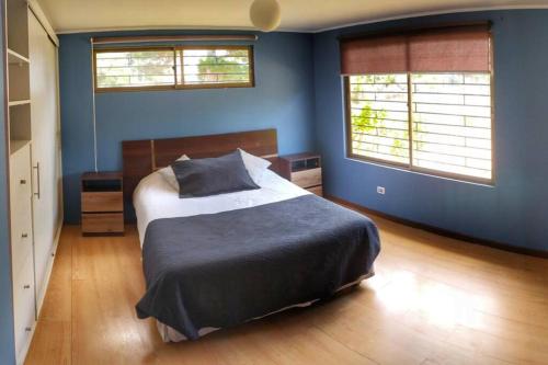 1 dormitorio azul con 1 cama y 2 ventanas en Casa de Costa, Campo y Relax, en Algarrobo