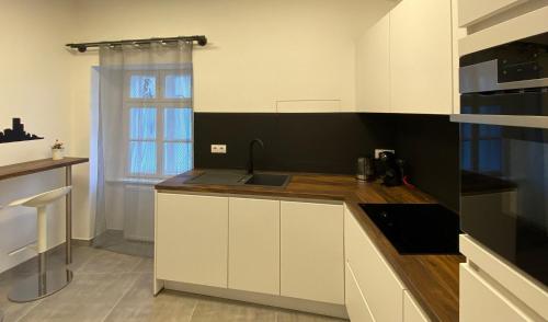 a kitchen with white cabinets and a sink at Hősök Tornya Apartman in Kőszeg