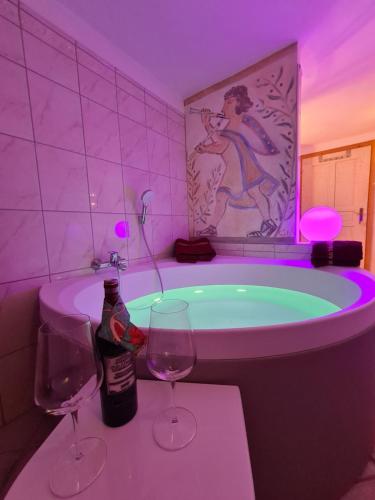 Ferienhaus Meins في كالز ام غروغلوكنير: حمام مع حوض استحمام مع كأسين من النبيذ