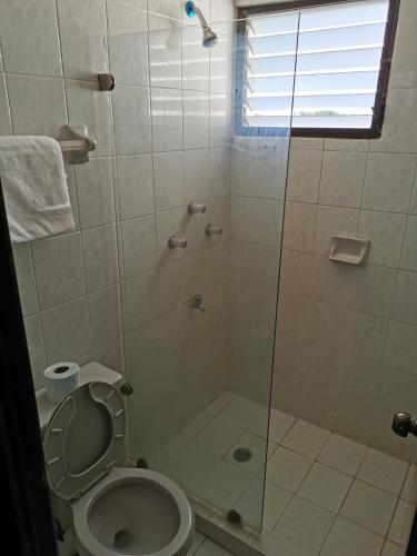 a bathroom with a toilet and a glass shower at Condominios Orca in Progreso