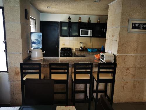 a kitchen with a counter with chairs and a blender at Condominios Orca in Progreso