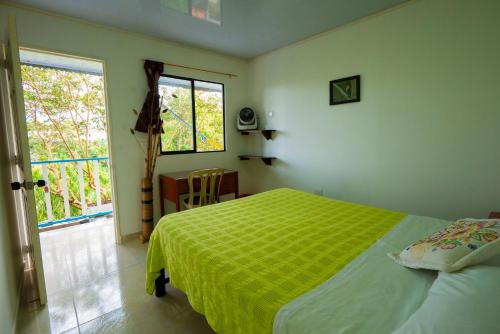 a bedroom with a green bed and a window at Casa Campesina Hostel in Armenia