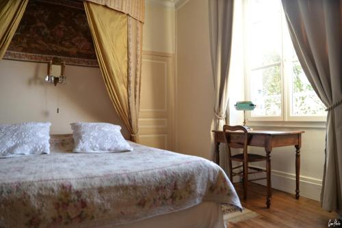 a bedroom with a bed and a desk and a window at L'Oustal in Bourges
