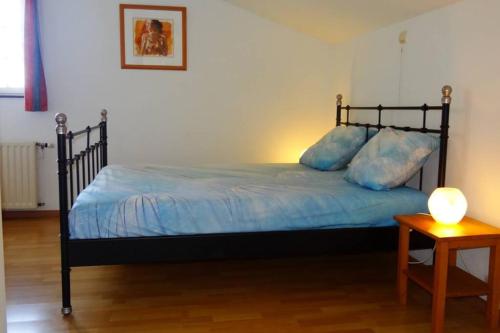 Un dormitorio con una cama con sábanas azules y una mesa. en Hoeve Espewey Cottage, en Hombourg