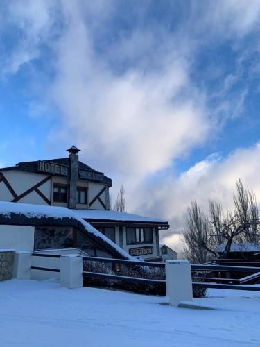 a house with snow on the ground in front of it at Hotel Sulayr in Sierra Nevada