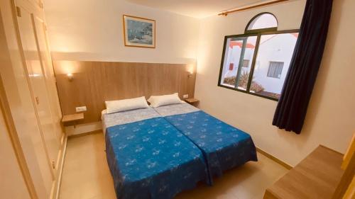 a bedroom with a blue bed with a window at Casthotels Fuertesol Bungalows in Caleta De Fuste