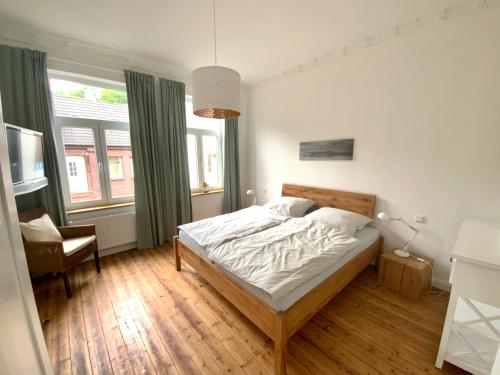 a bedroom with a bed and a chair and windows at FeWoEck Kogge in Eckernförde