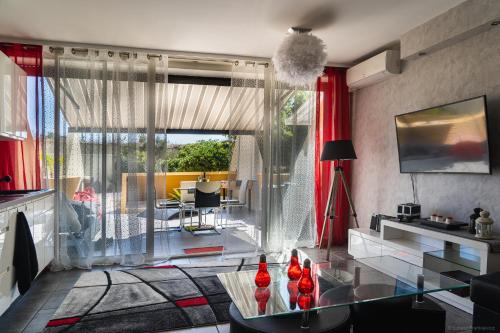 - un salon avec des rideaux rouges et une table en verre dans l'établissement Naturist village, beach side, ground floor apartment, au Cap d'Agde