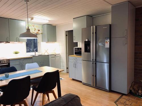 eine Küche mit einem Tisch und einem Kühlschrank aus Edelstahl in der Unterkunft Nommen Fishing Cottages in Vetlanda