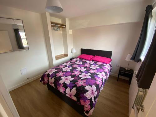 a bedroom with a bed with a purple and pink blanket at Arragon Short-Stay Apartments in Waterlooville
