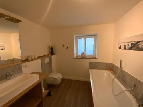 a bathroom with a tub and a toilet and a sink at FeWoEck Kogge in Eckernförde