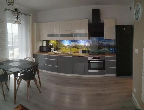 a kitchen with white cabinets and a table and a dining room at Apartament Przytulny Podolany in Poznań