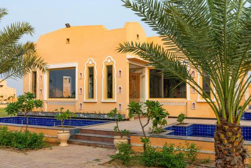 a house with a palm tree in front of it at Anand Bagh Resort & Spa by Ananta in Sālāsar