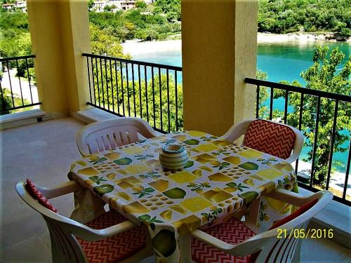 Una mesa y sillas en un balcón con vista al agua. en VILLAMAR beachfront apartments with FREE private parking, en Rabac