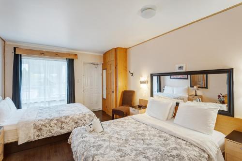 a hotel room with two beds and a window at Auberge Hotel Spa Watel in Sainte-Agathe-des-Monts