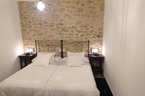 - un lit avec des draps et des oreillers blancs dans une chambre dans l'établissement Apartamentos Xert Escapadas en Castellón Cerca de Morella y Peñíscola, à Xert