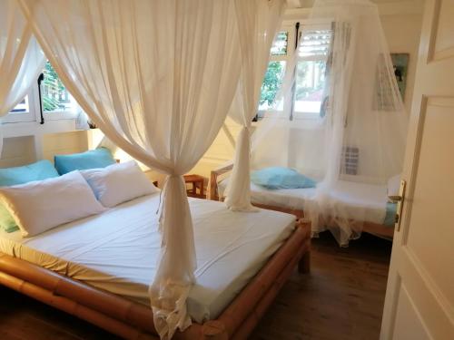 1 dormitorio con cama con cortinas y sofá en Blue Kaz Caraïb, en Pointe-Noire