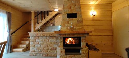 a stone fireplace in a room with a staircase at Vikendica Vila Despotovic in Kopaonik