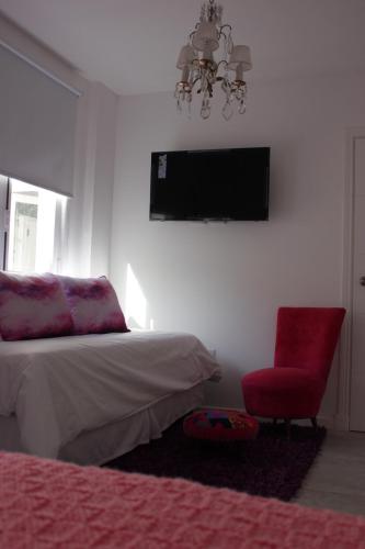 a bedroom with a bed and a chair and a television at Allegra Dalila Casa Hotel-Arte in Tandil