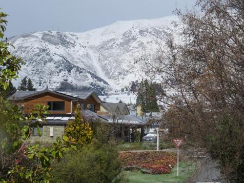 a house with a snow covered mountain in the background at Belvedere Apartments in Wanaka