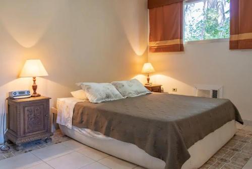ein Schlafzimmer mit einem Bett, zwei Lampen und einem Fenster in der Unterkunft Casa com seis suites, Praia de Pernambuco Guarujá in Guarujá