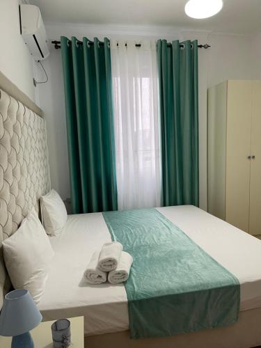 una camera da letto con tende verdi e un letto con asciugamani di Hotel Jurgen a Rinas