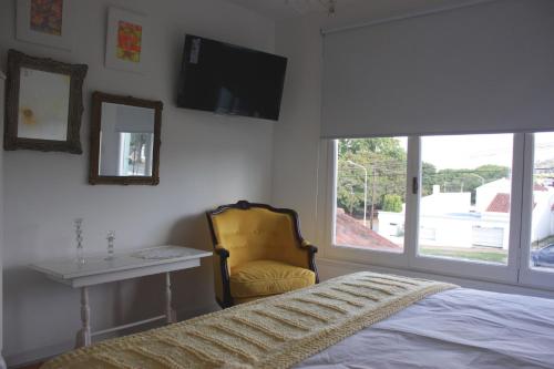 a bedroom with a bed and a chair and a window at Allegra Dalila Casa Hotel-Arte in Tandil
