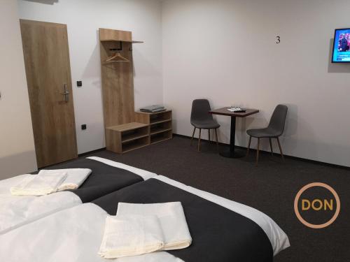 a bedroom with a bed and a table and chairs at Penzion DON in Třebíč