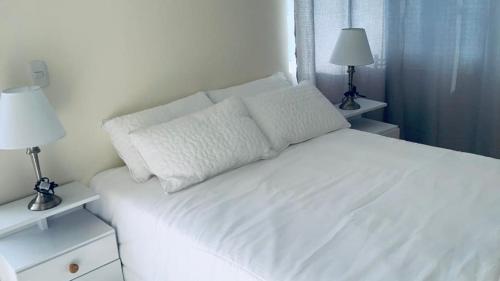 a bedroom with a white bed with two lamps at Penthouse - Vista Hermosa Apartments in Filandia