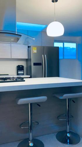 a kitchen with two bar stools at a counter at Penthouse - Vista Hermosa Apartments in Filandia