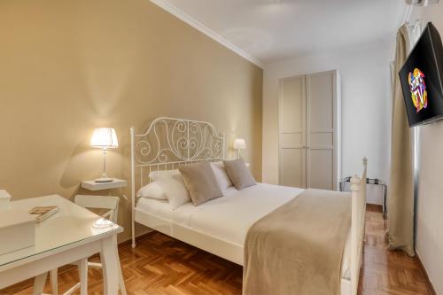 een slaapkamer met een bed, een bureau en een televisie bij ATRHOME penthouse Frattina in Rome