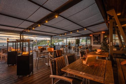 a patio area with tables, chairs and umbrellas at Hotel Zeezicht in Oost-Vlieland