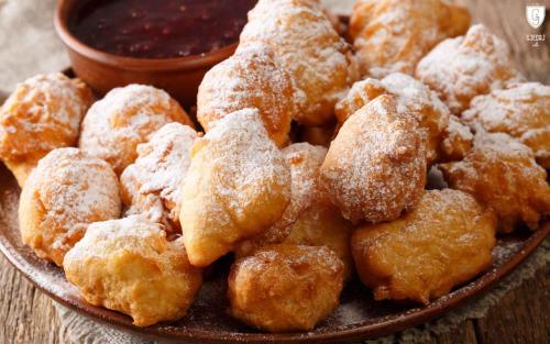 a plate of donuts covered in sugar next to a bowl of sauce at Villa Gjeçaj Guesthouse and Restaurant in Theth