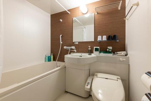 een badkamer met een toilet, een wastafel en een spiegel bij Hotel Route Inn Matsue in Matsue