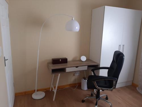 a desk with a black chair and a lamp at Shalom Self catering in Cape Town