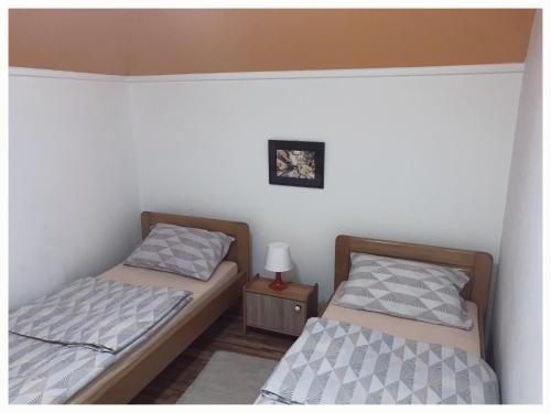 two twin beds in a room with a night stand at Vila Jelena, Tara in Kaludjerske Bare