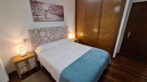 a small bedroom with a bed and a wooden door at Apartamento Capricho de Muxía in Muxia