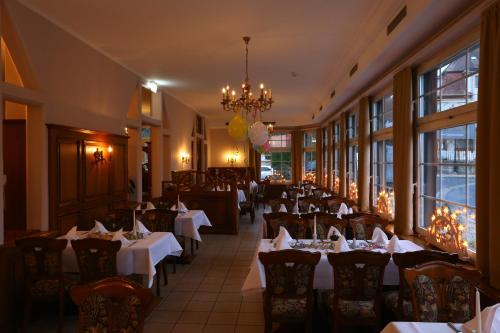 ein Restaurant mit Tischen, Stühlen und einem Kronleuchter in der Unterkunft Parkhotel Forsthaus in Tharandt