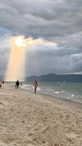 a woman walking on a beach with a rainbow in the background at Recanto da Sol in Florianópolis