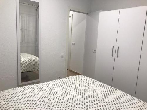 ein weißes Schlafzimmer mit einem Bett und einem Spiegel in der Unterkunft Un Descanso in San Bartolomé de Tirajana
