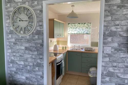 a kitchen with a brick wall and a clock at East Coast Chalets 58 at California Sands Dog Friendly in Great Yarmouth