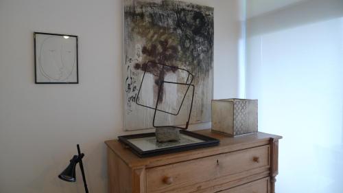uma cómoda de madeira com um candeeiro e uma pintura na parede em Las Villas de Cué em Llanes