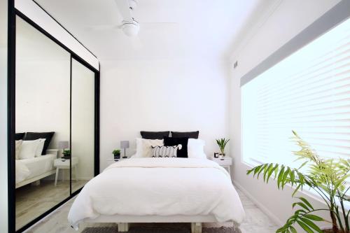 1 dormitorio con cama blanca y ventana grande en Beautifully renovated quiet unit in Cronulla, en Cronulla