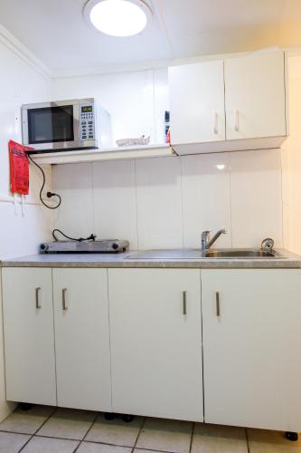 a kitchen with white cabinets and a sink and a microwave at Ningana Heritage Houses in Mudgee