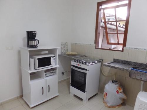 a small kitchen with a microwave and a stove at Canto da Cigarra I - Praia do Moçambique - FLORIANOPOLIS - SC in Florianópolis